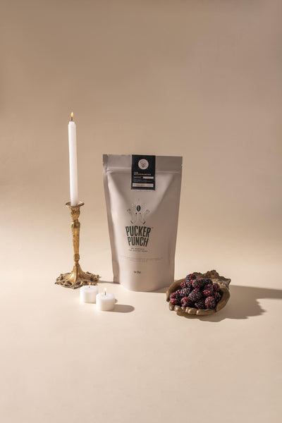 Necromancer Pucker Punch Coffee bag next to blackberries and candles.