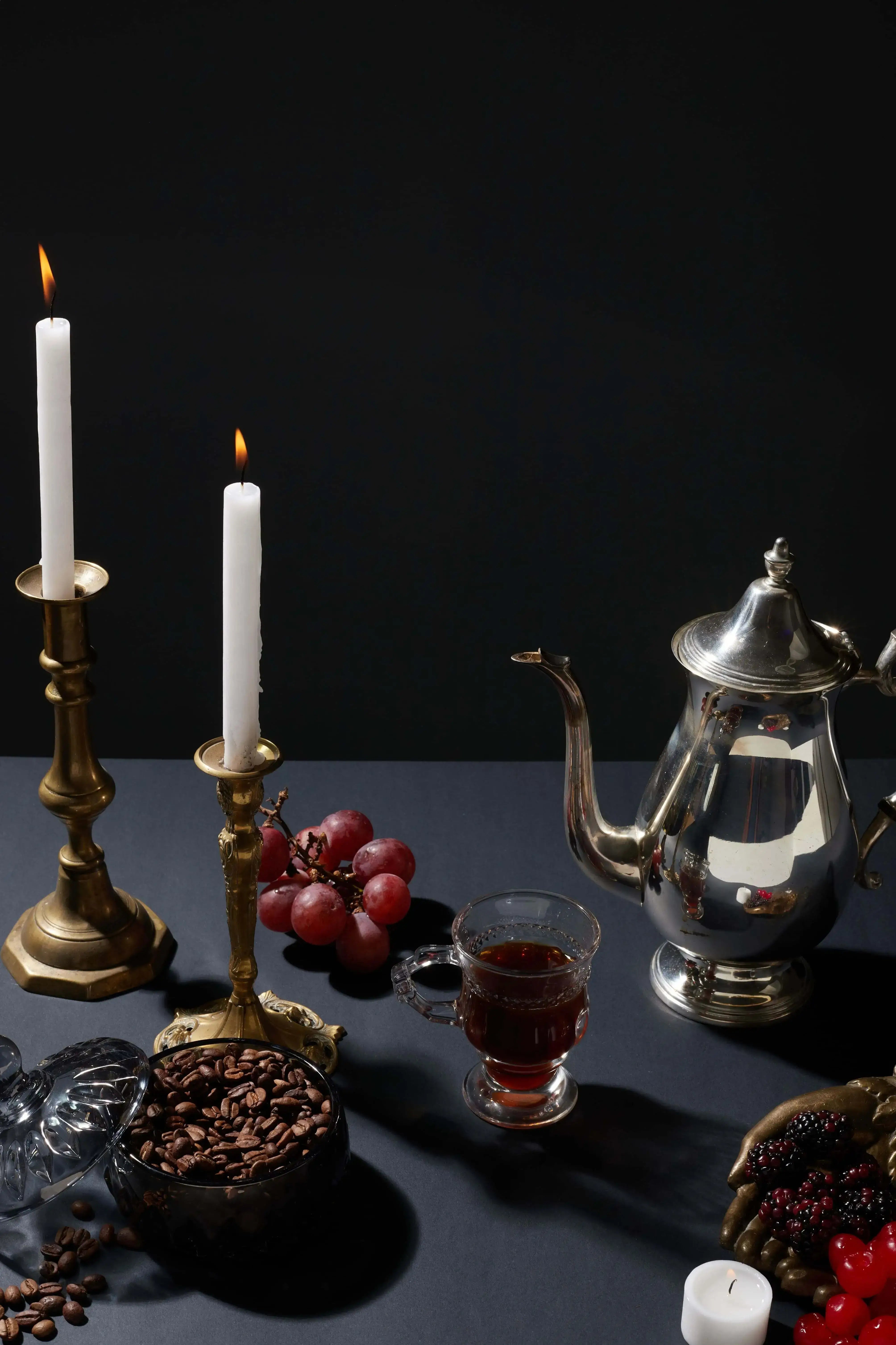 Pucker Punch coffee cup next to candles, grapes, raspberries and strawberries.